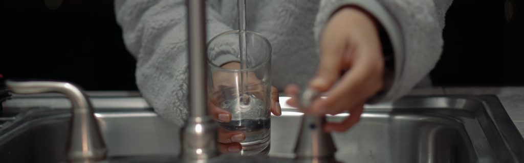 person holding clear glass container